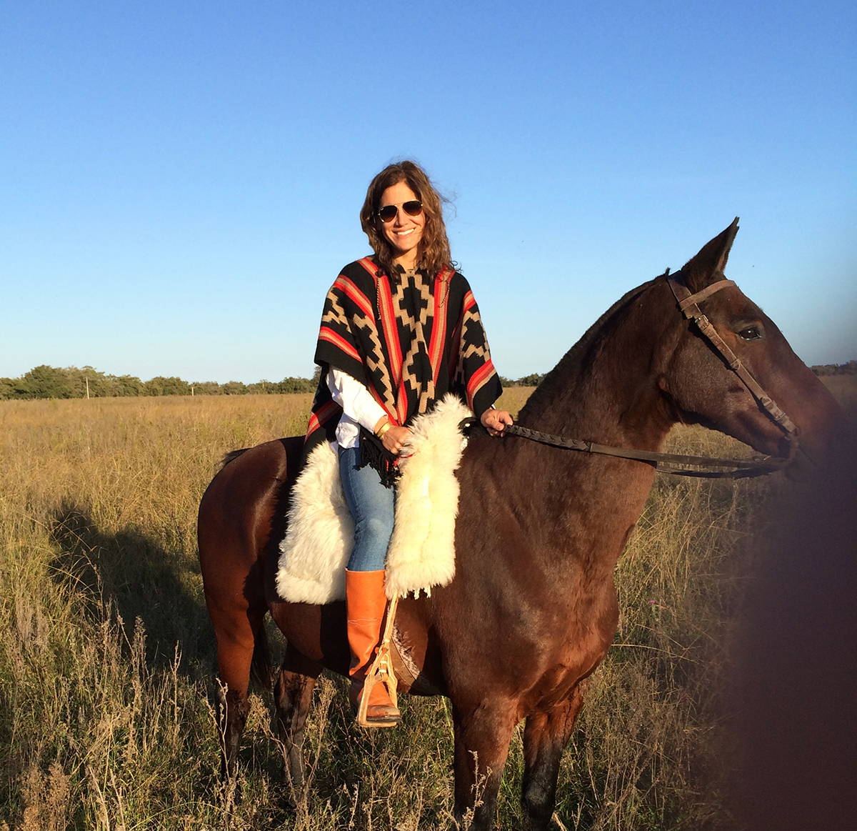 Elizabeth sits atop a horse wearing an Argentine poncho.