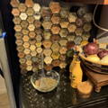A black fridge with more than 30 magnetic glass spice jars attached to it.