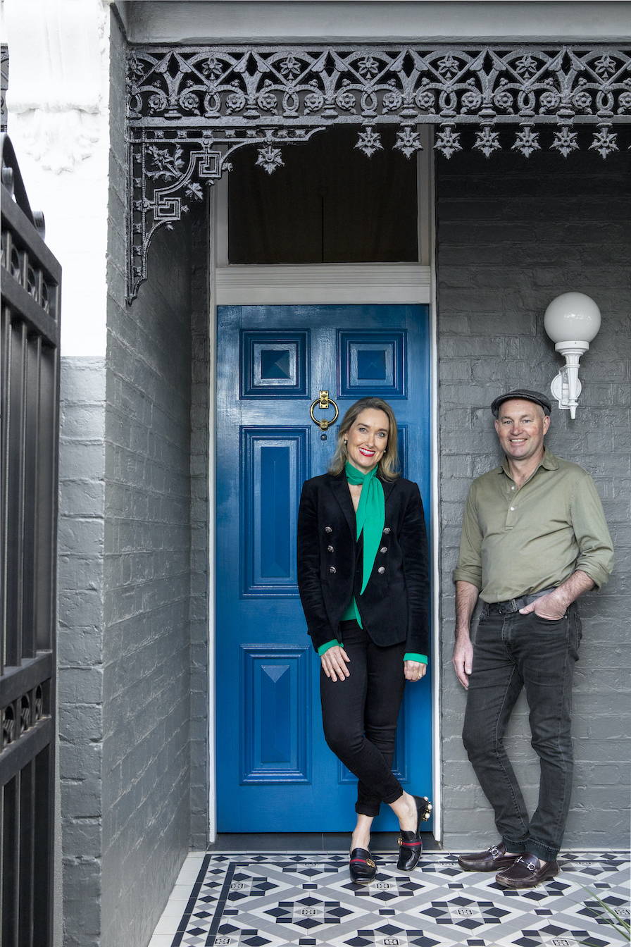 Husband and wife, Matt & Kate standing outside their blue front door