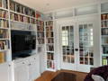 Wall unit built to fit doorway and features cabinets and space for TV.