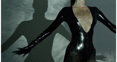 model wearing black pludge bodysuit with arms out. 