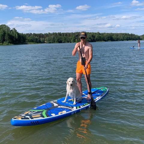 Boy inflatable paddleboarding with his dog in Alberta lake