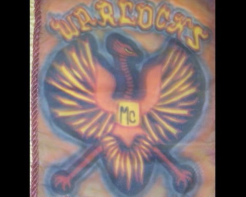 Close-up photograph of the Warlocks Motorcycle Club patch showing the Phoenix emblem in orange, red, and gold colors