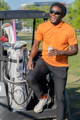 Happy golfer enjoying a drink while leaning on a golf cart next to his golf bag.