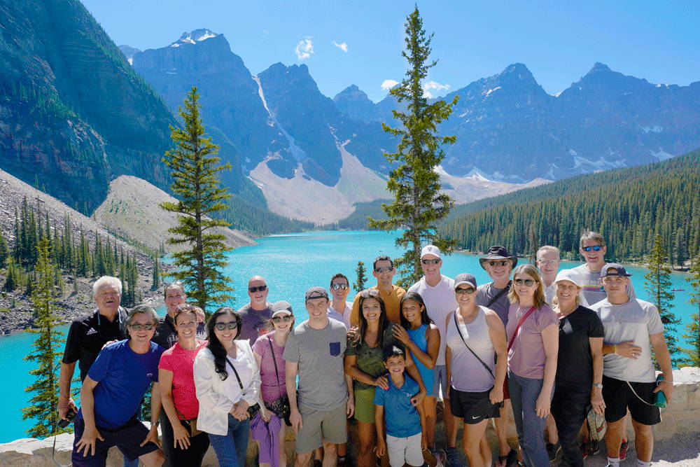 Group of people posing with Banff water and mountains in background
