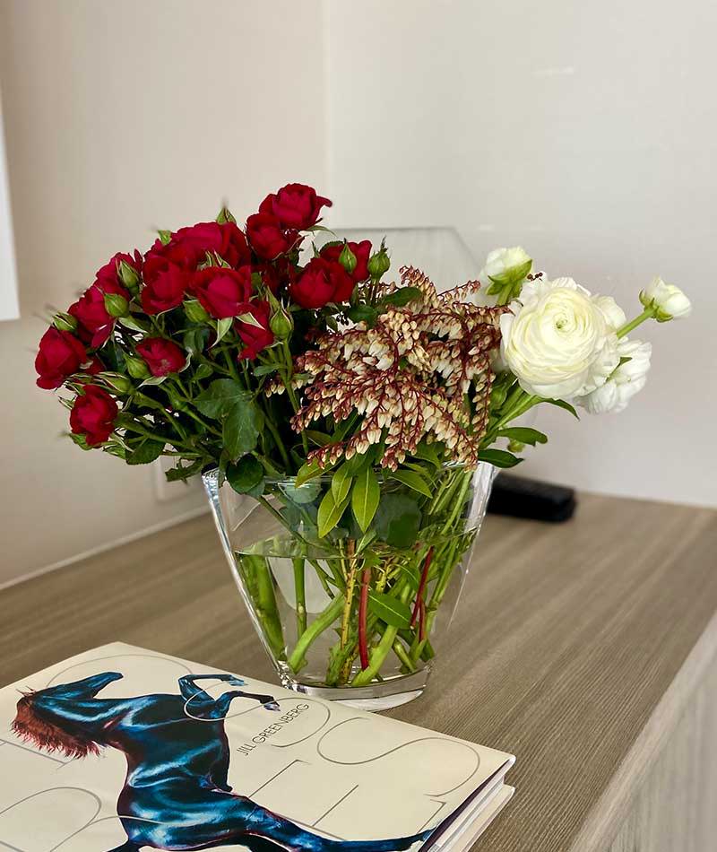 Bouquet of red and white flowers placed on a cabinet next to a book