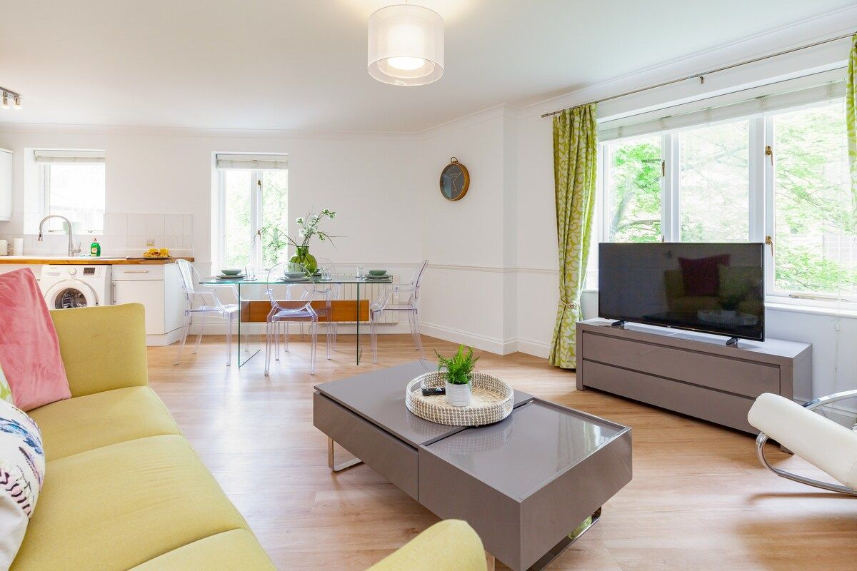 Living room with large yellow sofa facing a coffee table and TV