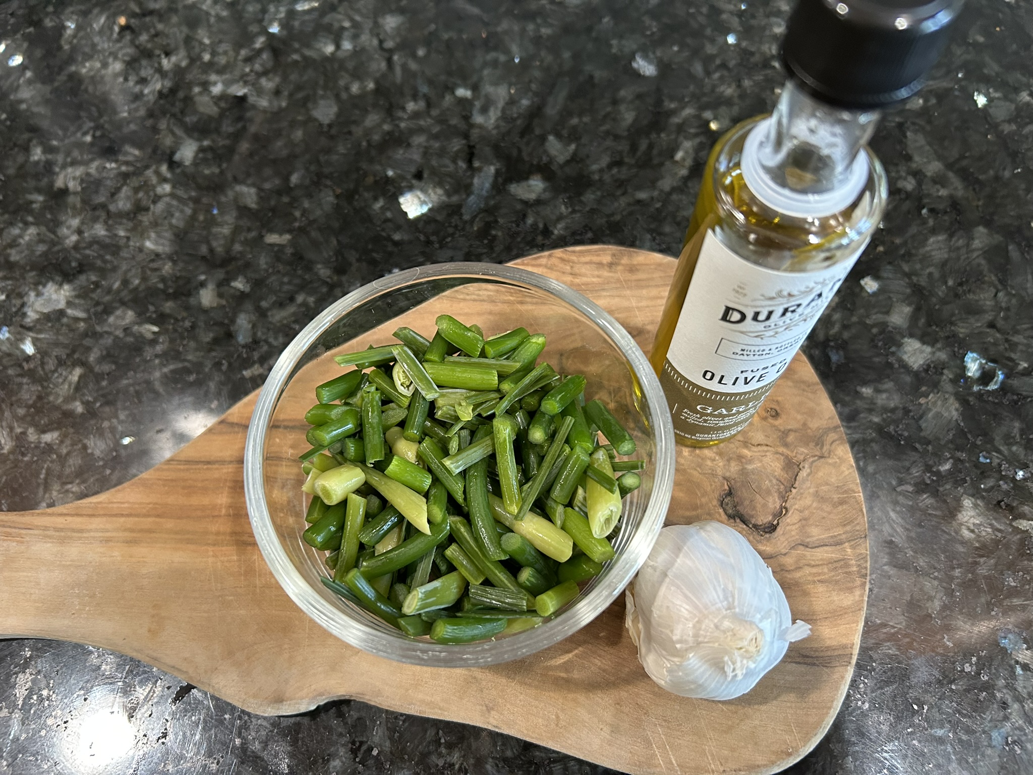 Garlic scapes, olive oil, and garlic on a cutting board