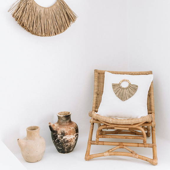 White boho cushion on a texture boho style chair. Cushion featuring a boho Cushion Accessory made from seagrass.