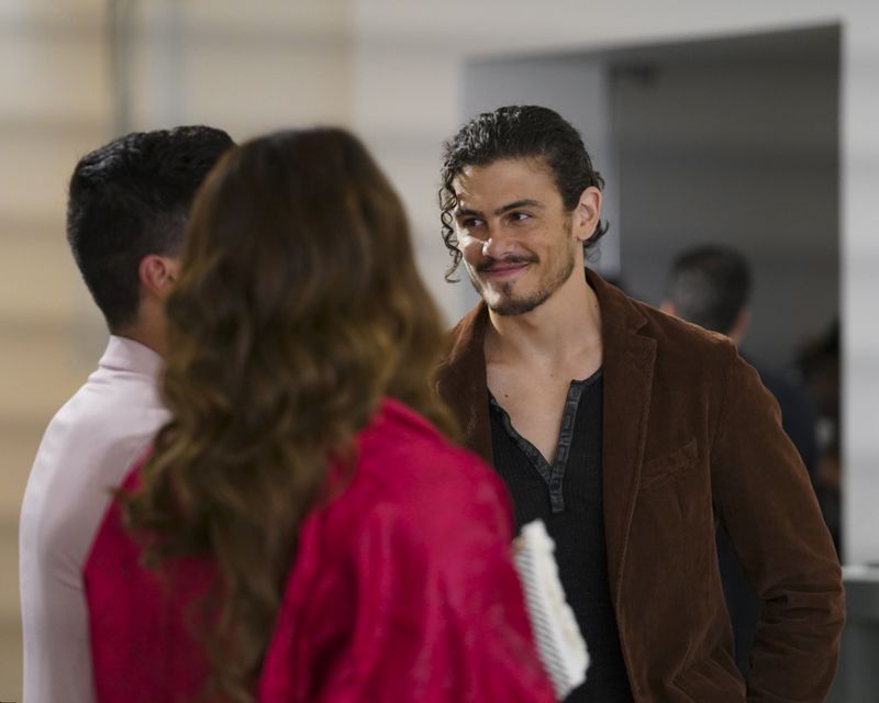 Gael smiles while talking to two other characters who are facing him.