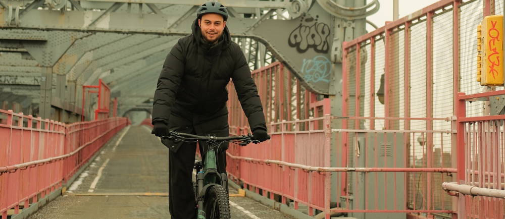 a man riding an electric mountain bike across a graffiti covered bridge in new york city