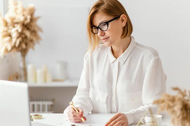 Vue de face d'une belle femme au travail avec un stylo et un ordinateur portable