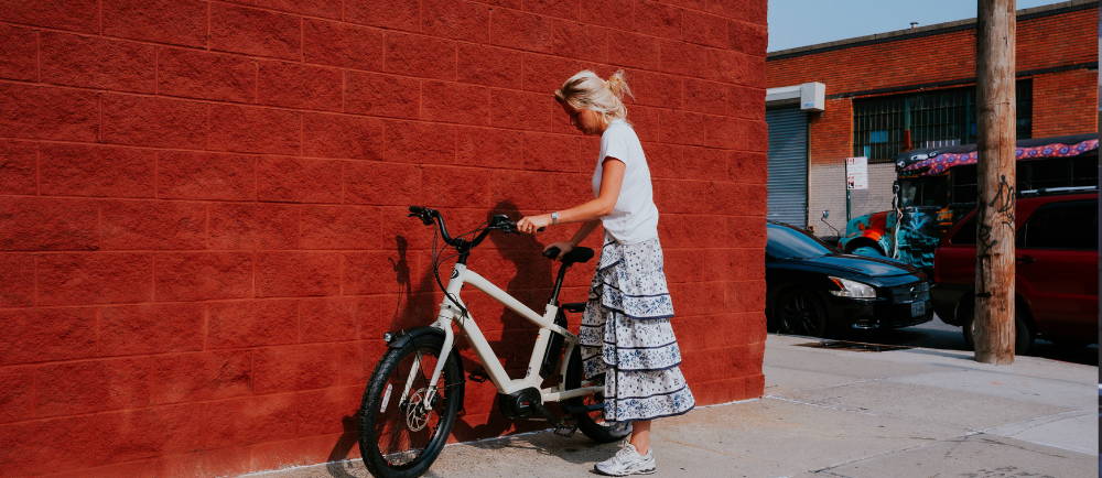 A woman standing next to a brick building and an electric bike