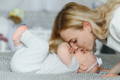 Mother gently kissing her baby during close bonding time on a soft surface