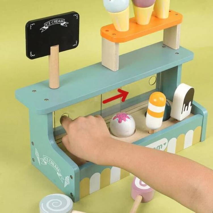 Hand moving a small plastic window on the Montessori Ice Cream Shop.