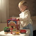 Little girl playing with a colorful Montessori Santa's Workshop featuring a box filled with wooden Christmas-themed figurines.