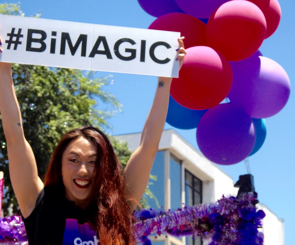 Nick at a ambi parade, holding a sign that reads hashtag bi magic.