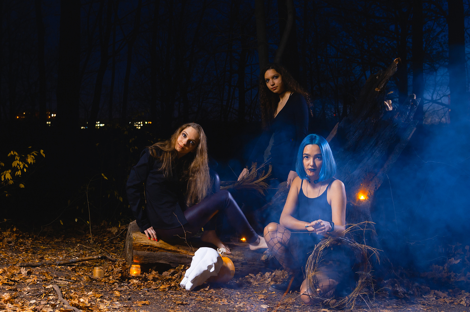 /A group of women sitting near woods with candles and smoke around them.