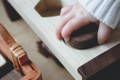 A baby's hand holding a wooden piece of a Montessori shape puzzle. 