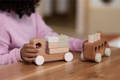 A little girl playing with a wooden Montessori train toy on her wooden desk. 