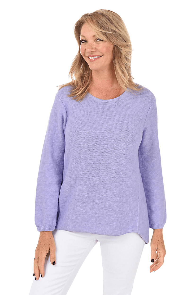 A woman wearing a light purple sweater and white pants
