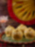 A visually appealing arrangement of yellow sweets on a banana leaf, with a festive background.