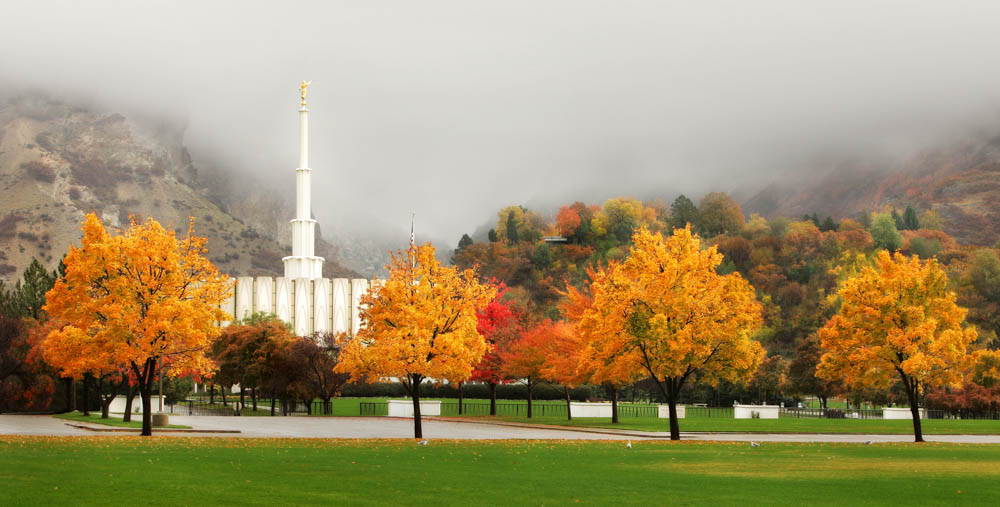 Panoramic photo of the Provo Temple surrounded by autumn trees and fog.