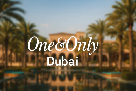 Blurred view of the One & Only Dubai resort building with arches, surrounded by palm trees and a reflecting pool, featuring overlaid text "One & Only Dubai".