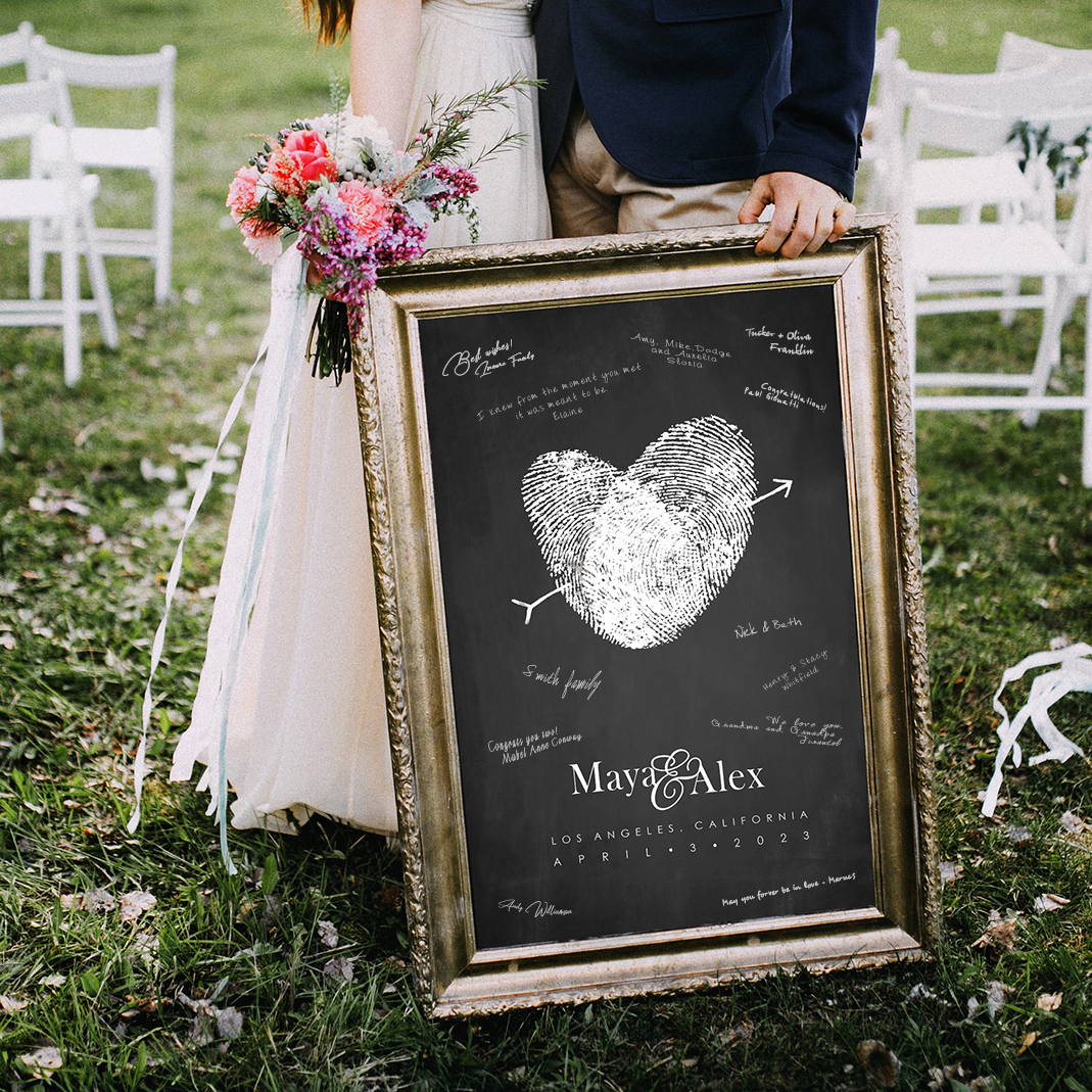 bride and groom holding fingerprint wedding guest book alternative with signatures