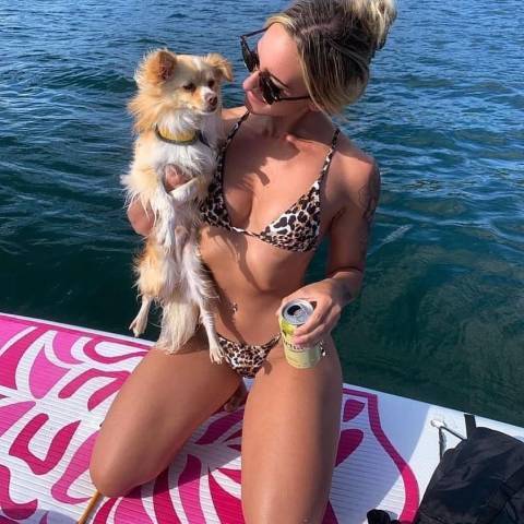 Customer with her dog seating in TIKI best inflatable paddle board for dogs and smile