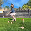 Girl playing with a Montessori Golf Set in the backyard.