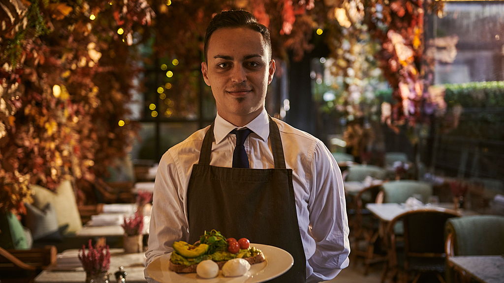 Waiter standing holding plate of breakfast food in a restaurant