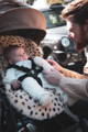 a father next to a babyzen yoyo pram with a baby in it who is on a leopard pram style sheepskin liner from Baa Baby