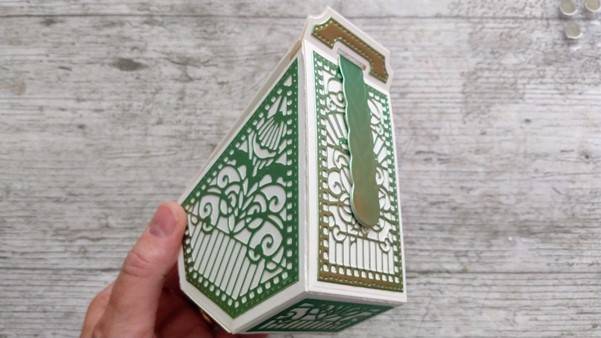 a hand holding a green and white box