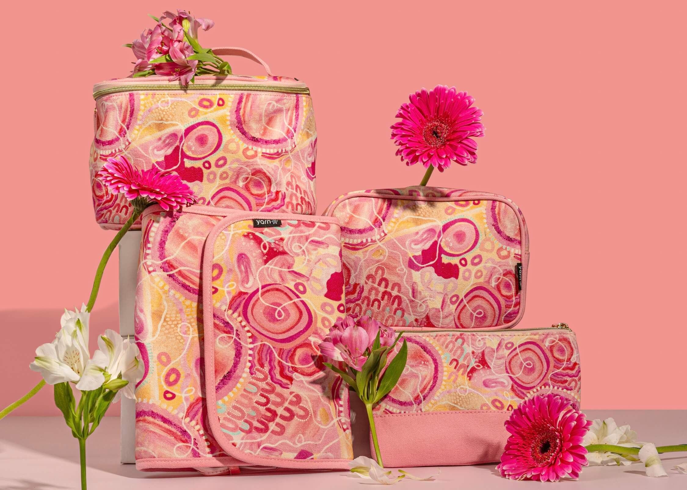 pink cosmetics & toiletry bags with artwork by Indigenous artist Kinita-Lee McCartney with a pink background and pink flowers around