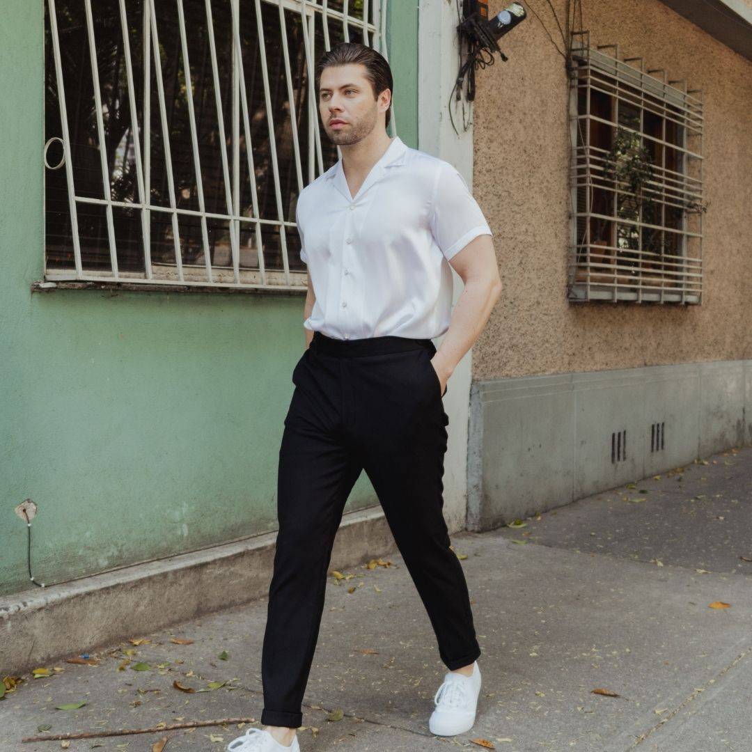 model walking down a sidewalk wearing white shoes black high waisted pants and a short sleeve white silk shirt from 1000 kingdoms