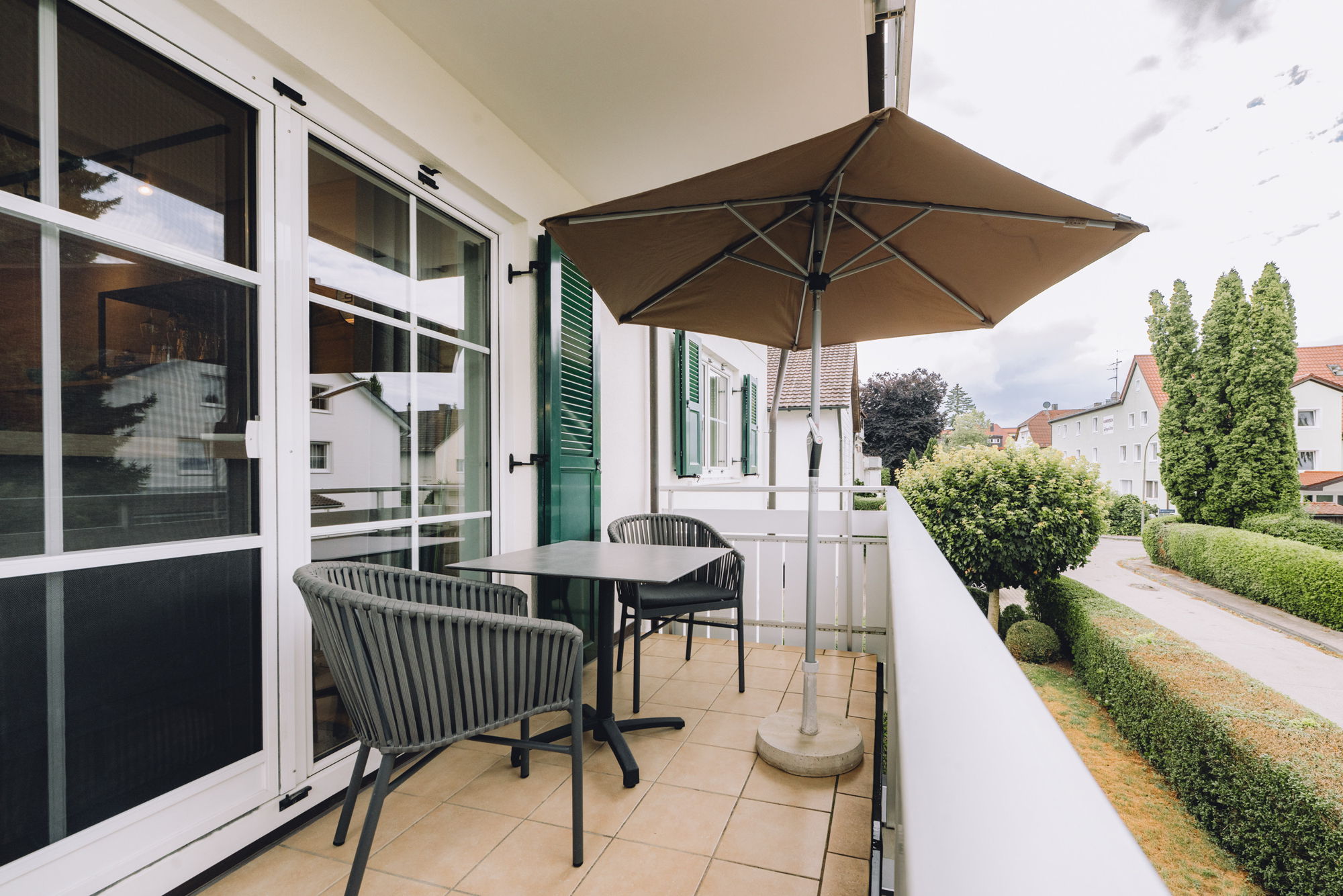 Balkon mit Sonnenschirm, Stühlen und Esstisch.