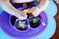 Baby eating vegetables from a silicone kitchen set.