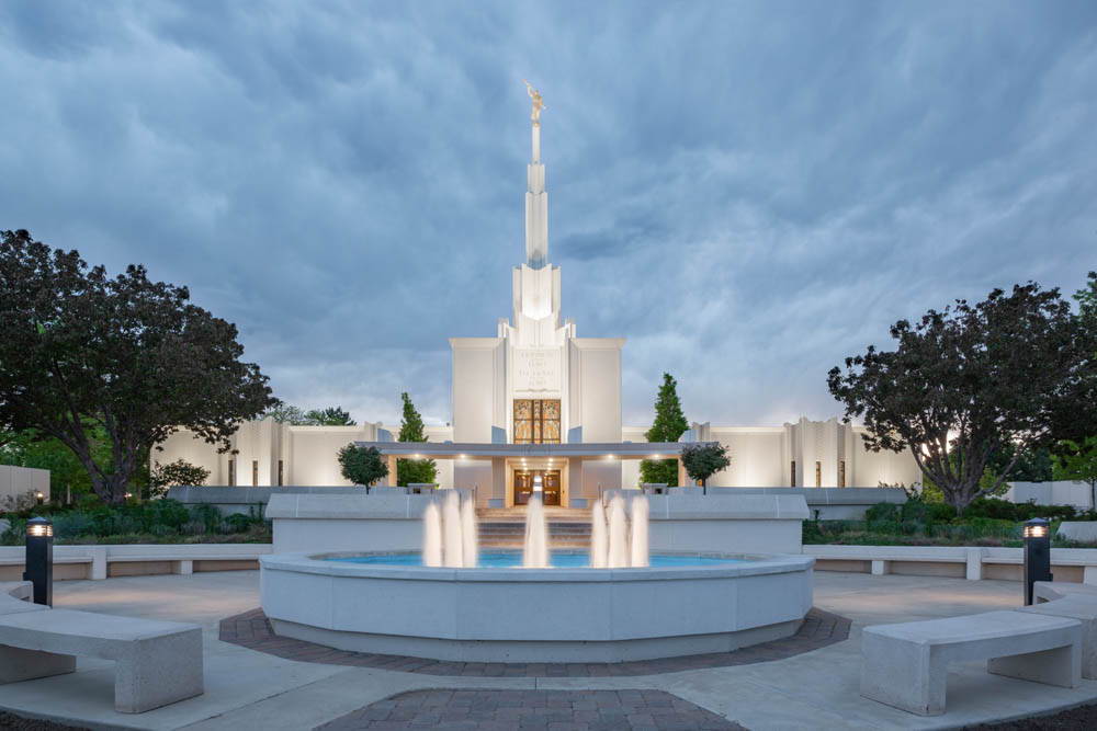 A glowing fountain in front of the Denver Temple. The sky is filled with clouds.