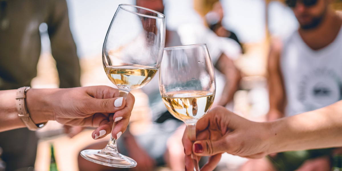 Two filled glasses of white wine toasting.