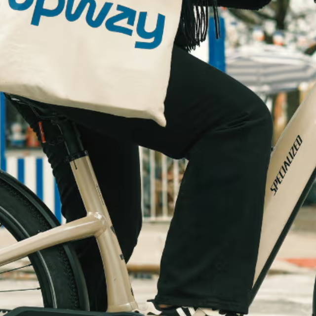 a woman riding an electric bike in the city and carrying an upway handbag