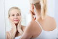 woman looking in the mirror noticing the skin benefits of using collagen to reduce wrinkles