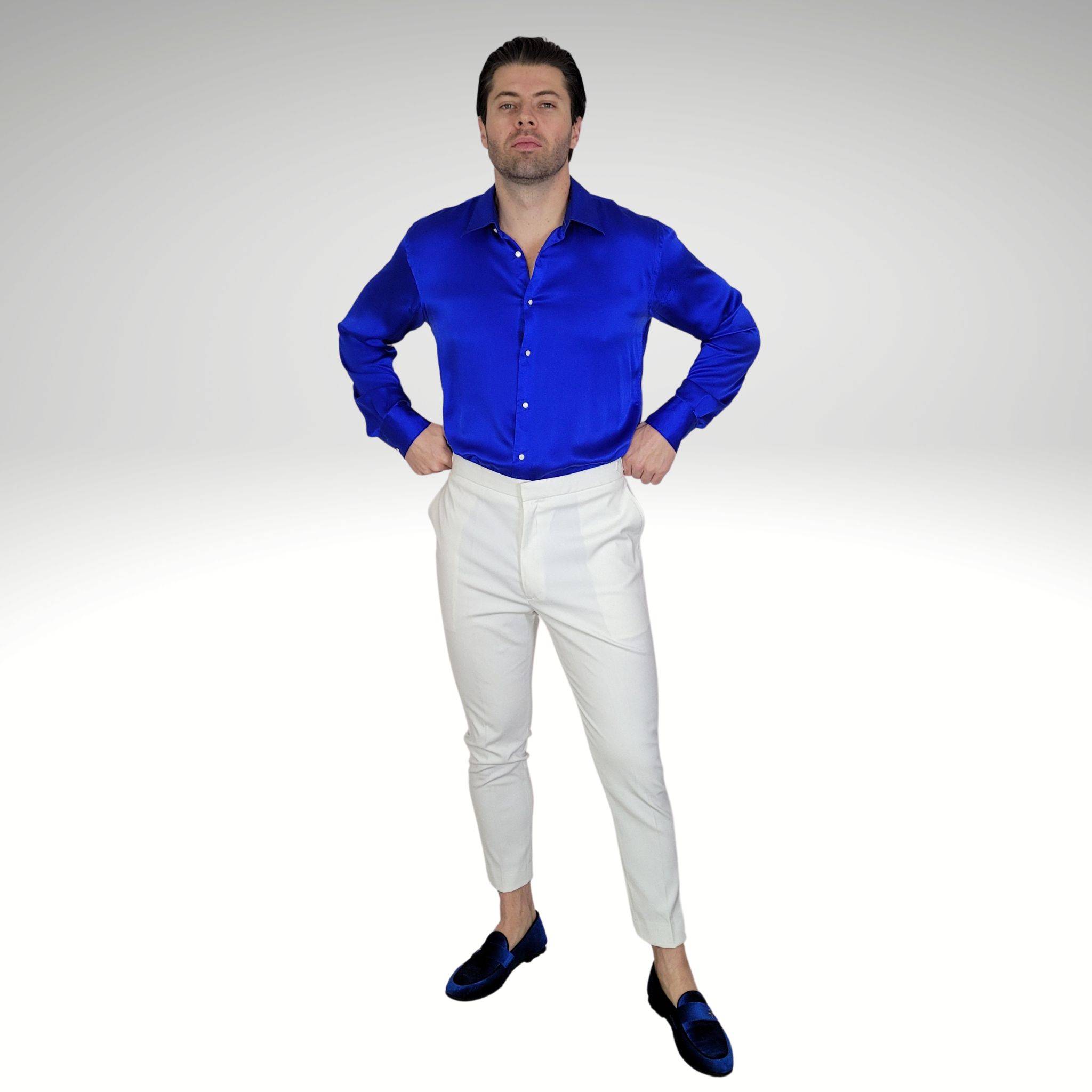 model wearing a blue silk shirt with white suit pants and blue velvet loafers