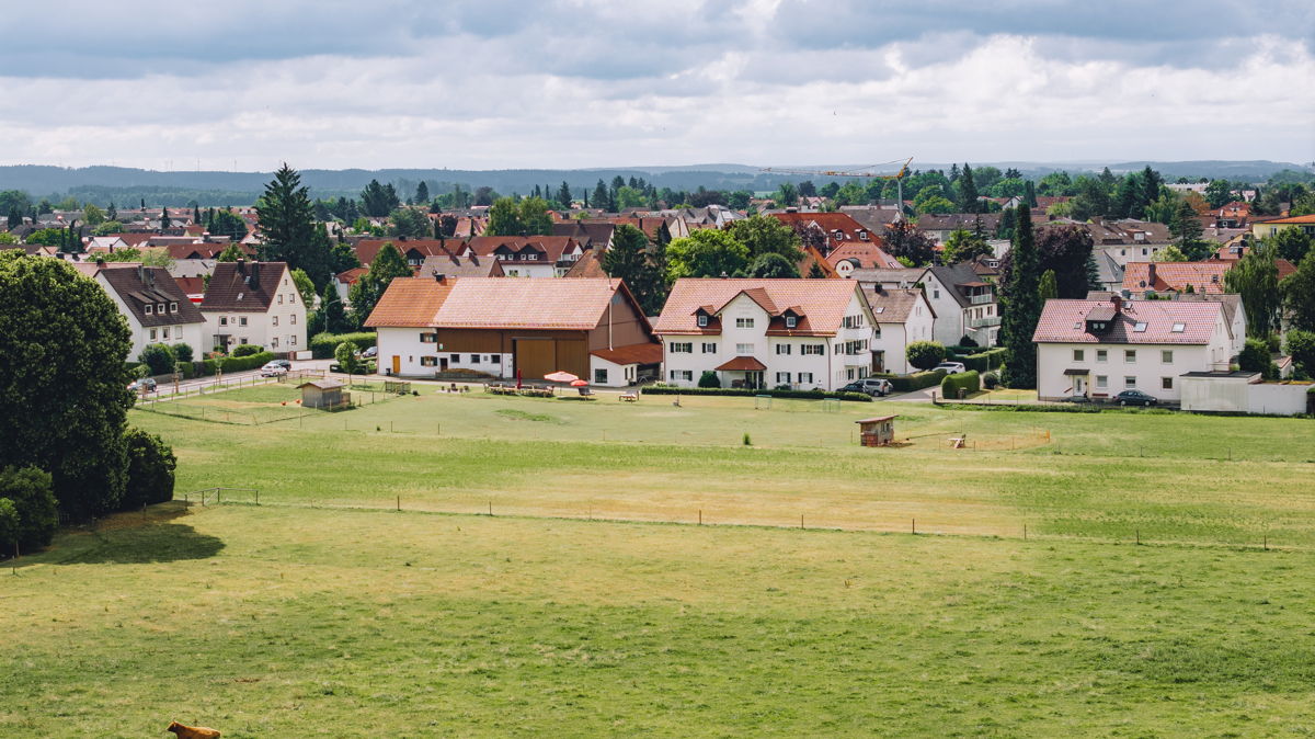 Entfernte Luftansicht des Hofs, im Vordergrund grüne Wiesen und im Hintergrund Bad Wörishofen.
