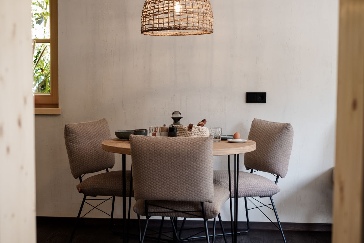 Essbereich mit rundem Tisch und offener Küche im Apartment Waldgeflüster in Mittelberg.