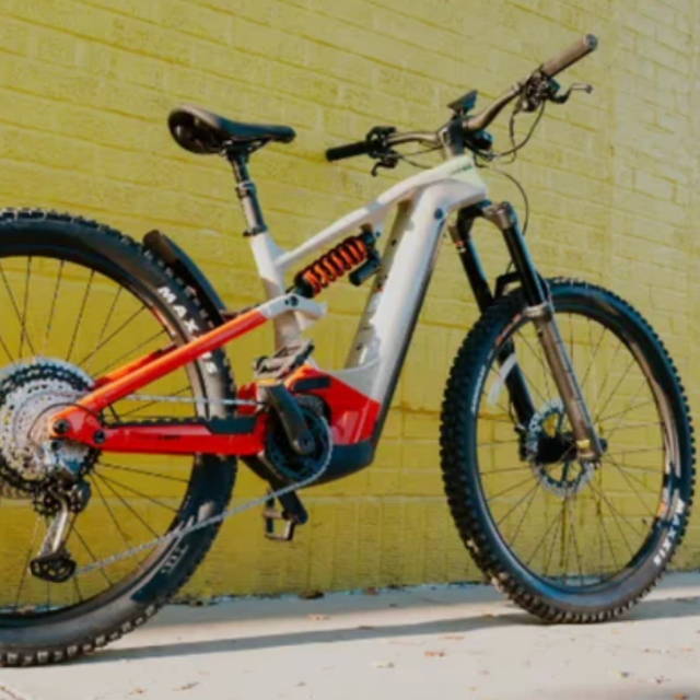 a full suspension electric bike in front of a yellow wall