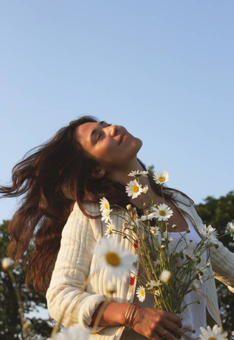 Woman holding flowers against a blue sky