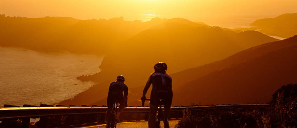 Two cyclists on road bike during sunset
