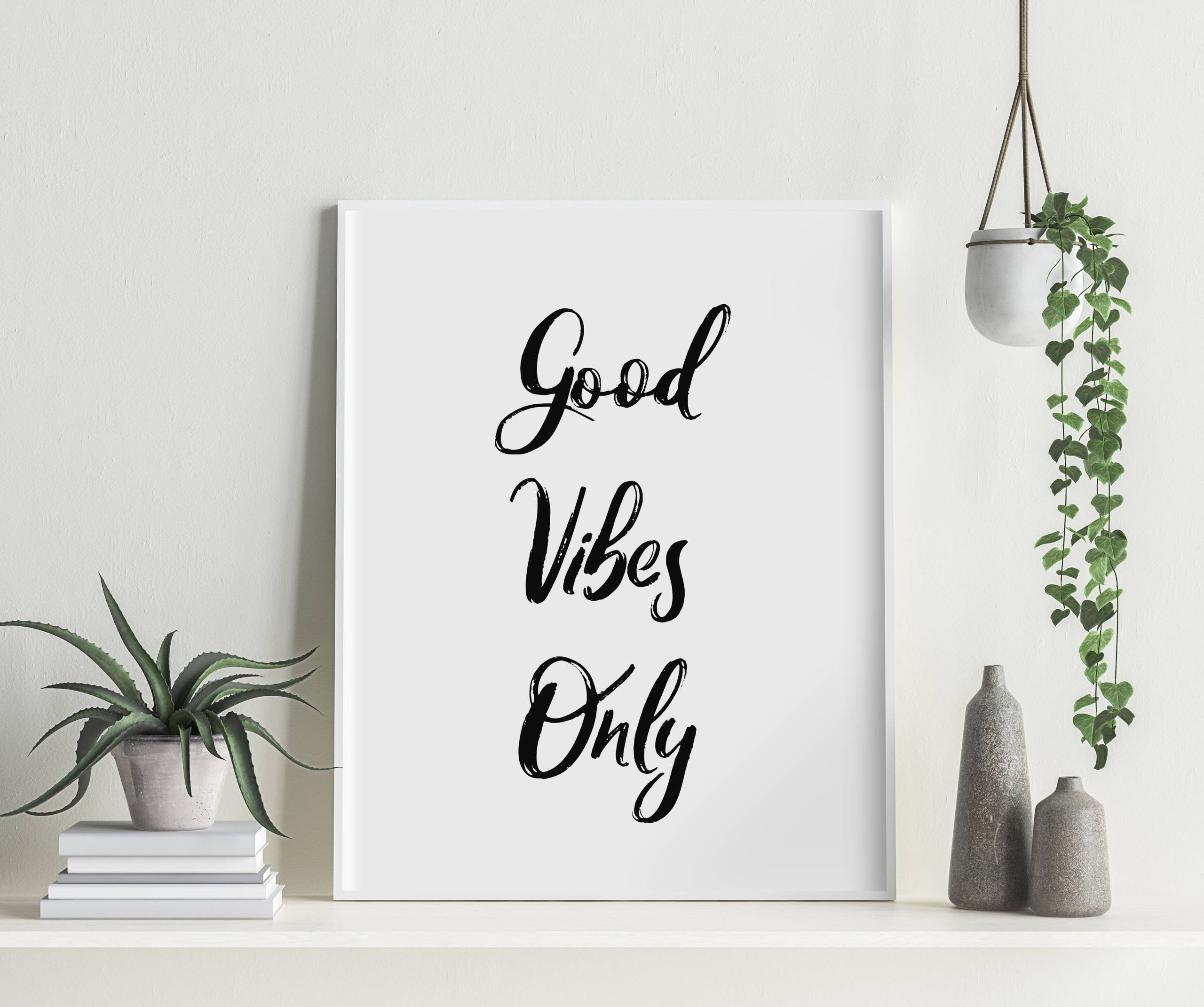Shelf with decorations and ornaments, featuring a large typographical print with the text 'Good Vibes Only'