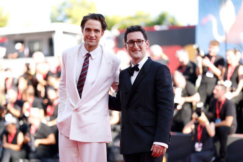 Image may contain: Antony Costa, Robert Pattinson, Clothing, Formal Wear, Suit, Blazer, Coat, Jacket, Accessories, and Tie